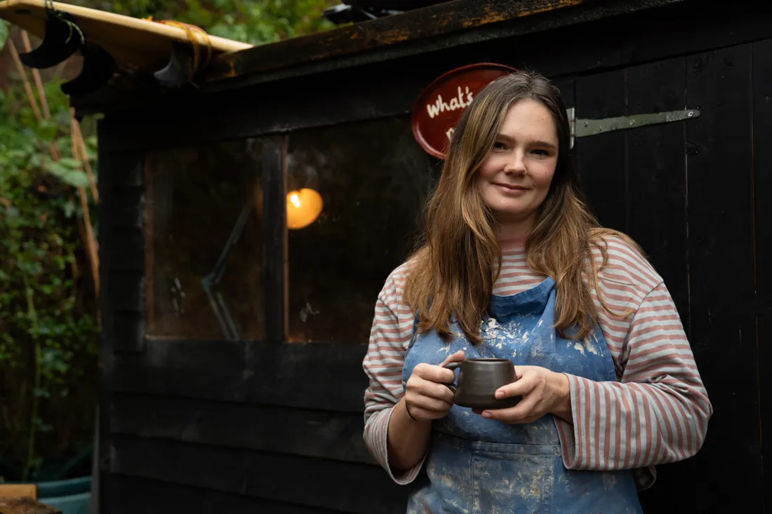 Isa holding a mug outside her garden pottery studio